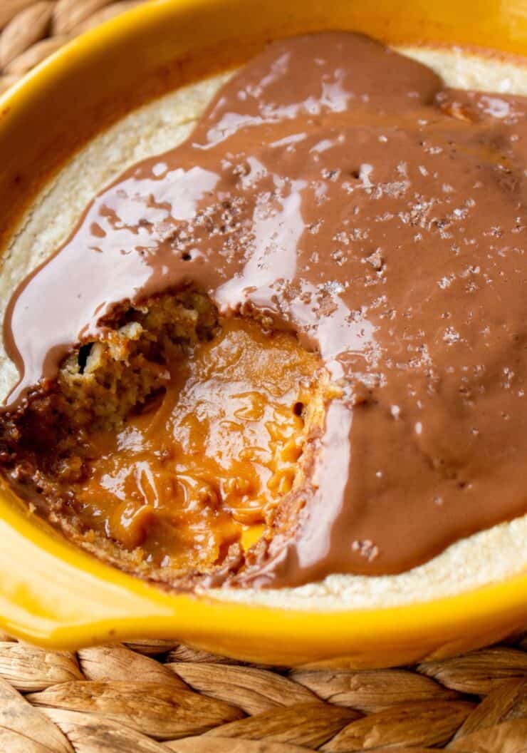 Baked cake in ramekin oozing peanut butter filling and topped with chocolate.