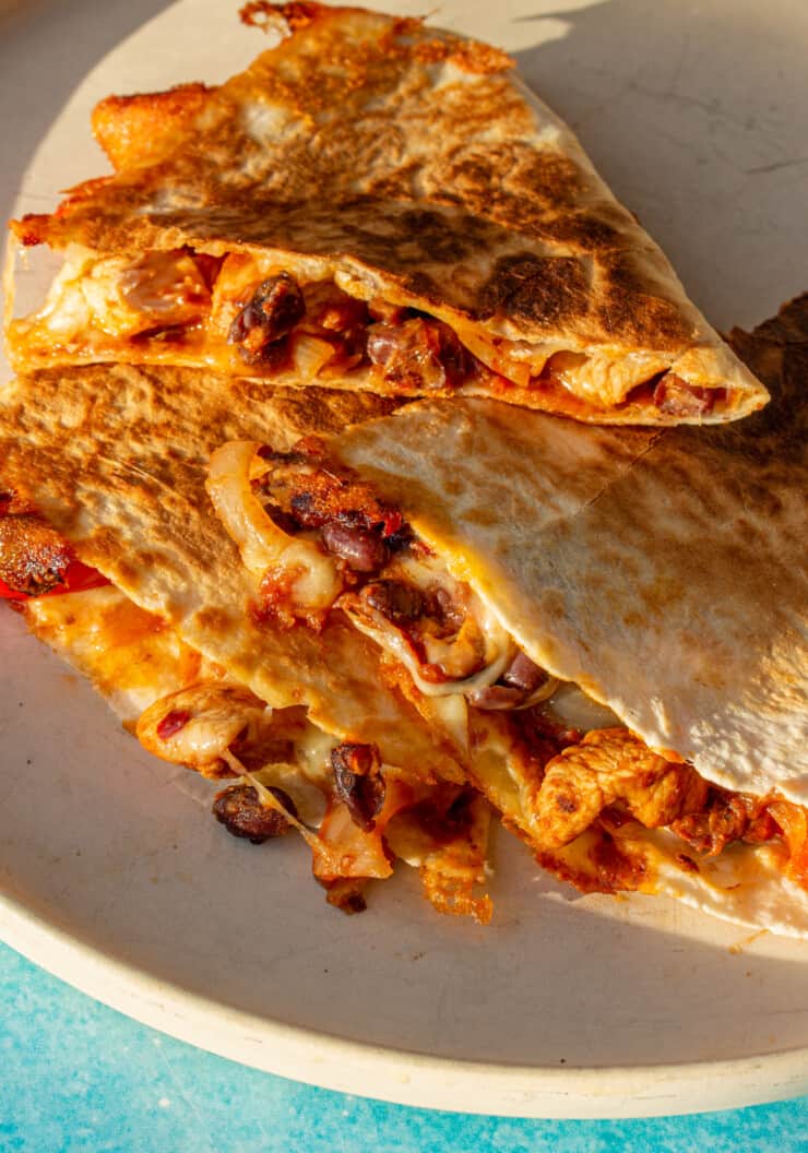 Chicken Quesadillas in tortilla wraps with black beans, tomatoes and cheese piled on top of each other.