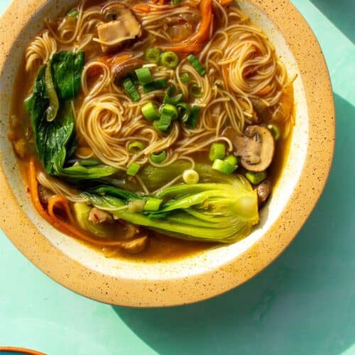Vegetable soup with pak choi, noodles, carrots and mushrooms in a bowl.