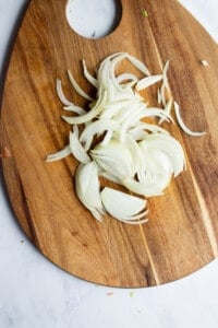 Sliced onion on a wooden chopping board.