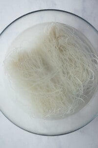 Vermicelli noodles in boiling water in a glass bowl.
