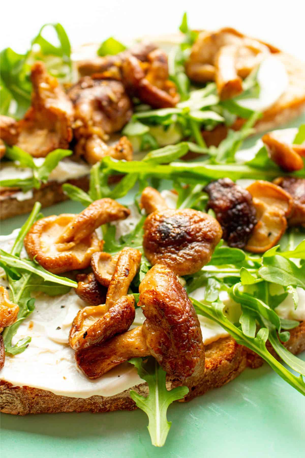 Close up of mushrooms, and rocket and cream cheese on toast.