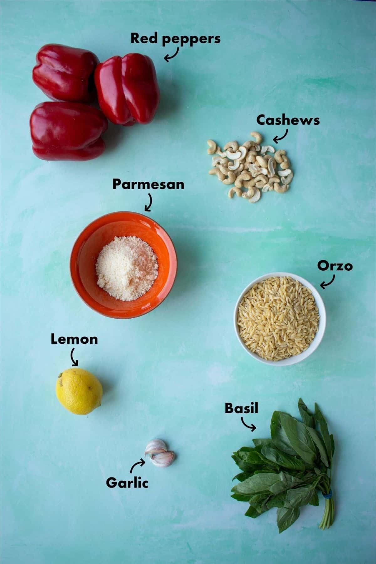 Ingredients to make red pepper pesto laid out on a pale blue background and labelled.