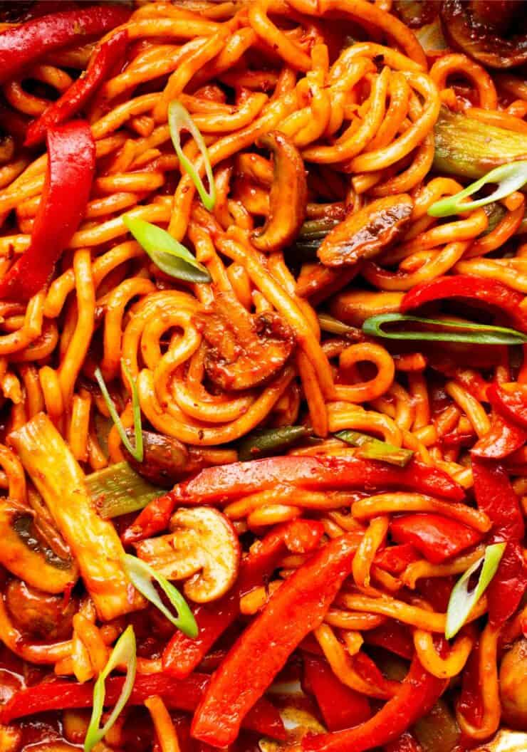 Close up of noodles in tomatoey sauce with vegetables.
