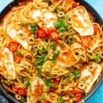 Halloumi pasta in a pan with spaghetti, slices of spring onion, red chillies and golden browned halloumi.