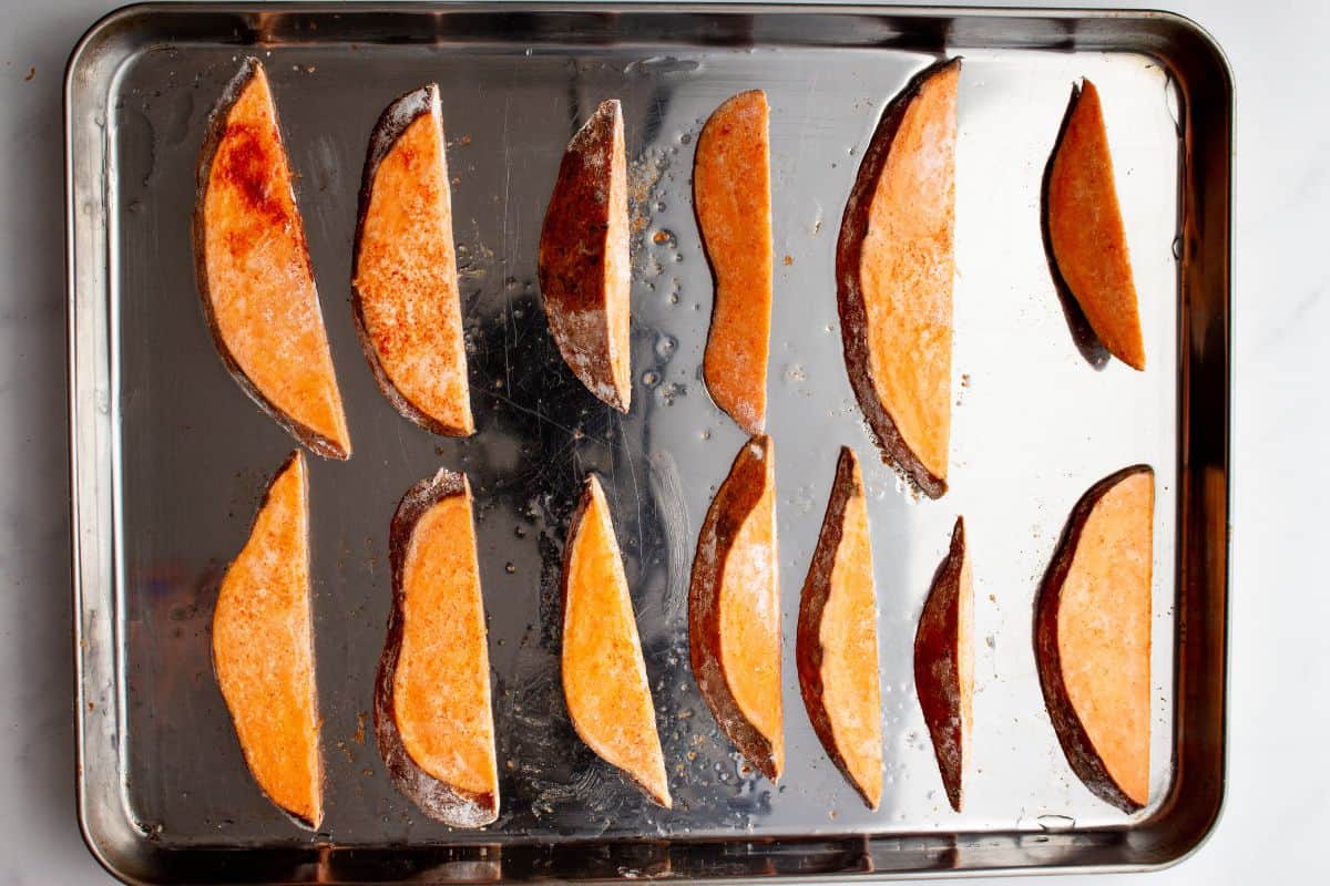 Sweet Potato slices distributed evenly on a stainless steel baking tray.