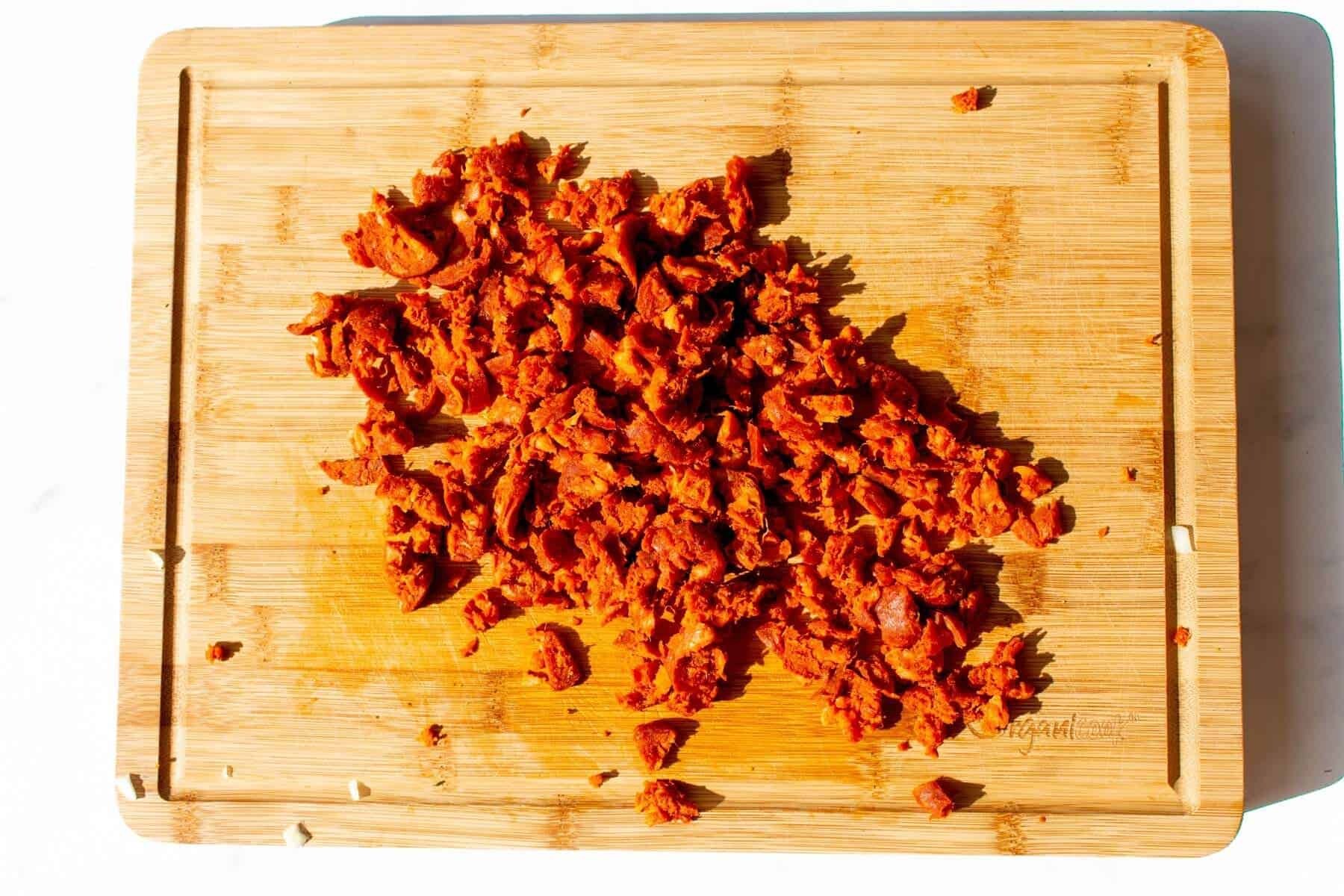 Chorizo finely chopped on a wooden chopping board.