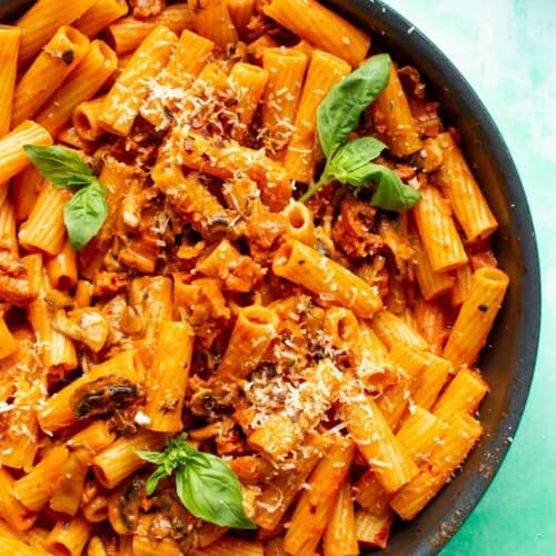 Creamy Chorizo Pasta in a pan topped with grated parmesan and fresh basil leaves.