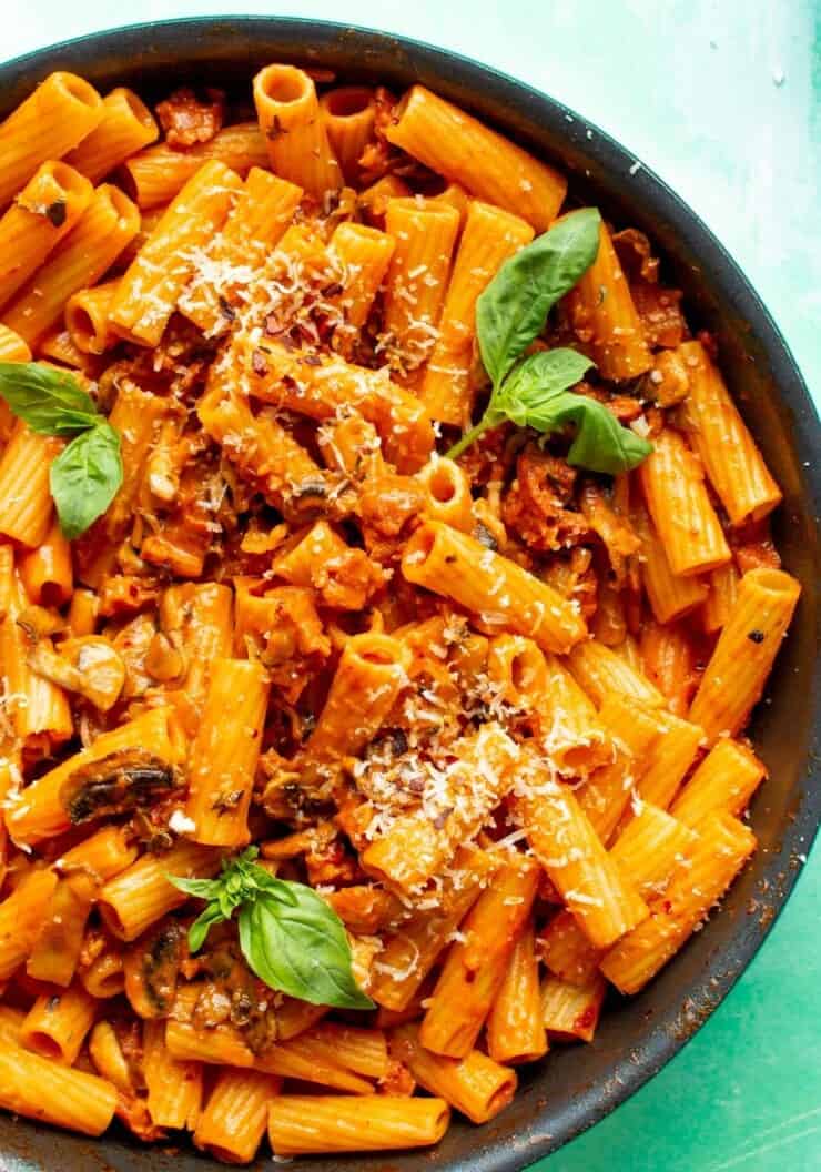 Creamy Chorizo Pasta in a pan topped with grated parmesan and fresh basil leaves.