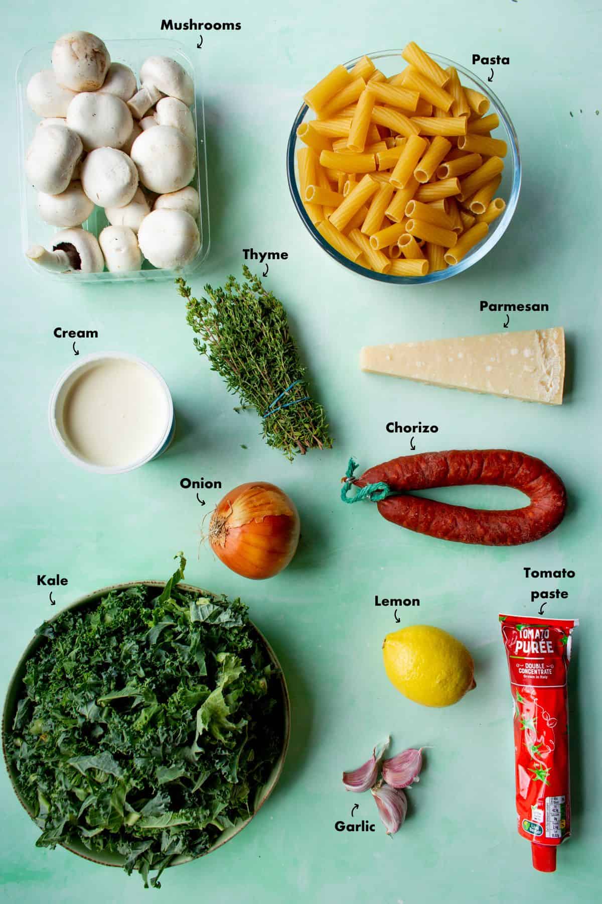 Ingredients to make chorizo pasta recipe laid out on a pale blue background and labelled.