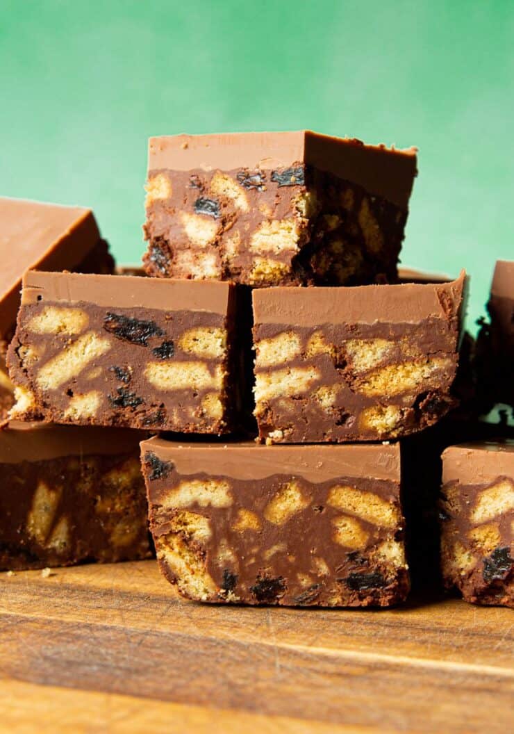 Tiffin Cake square slices, containing biscuit, raisins and thick chocolate topping stacked on top of each other.