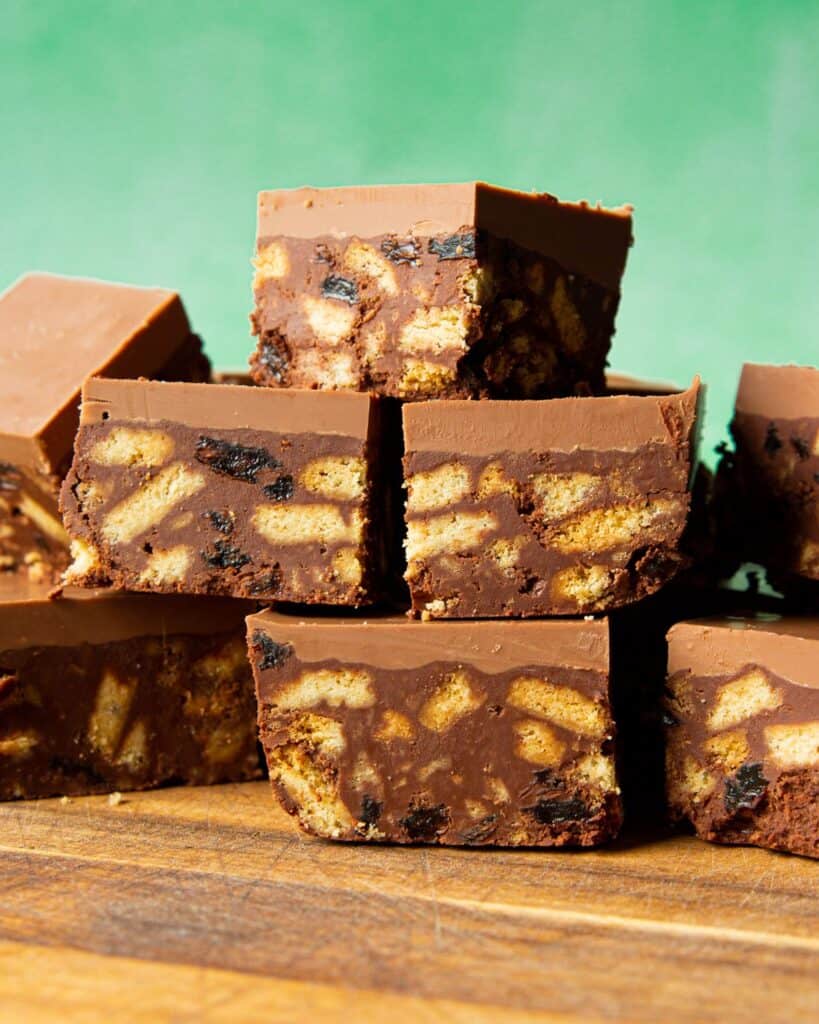 Tiffin Cake square slices, containing biscuit, raisins and thick chocolate topping stacked on top of each other.