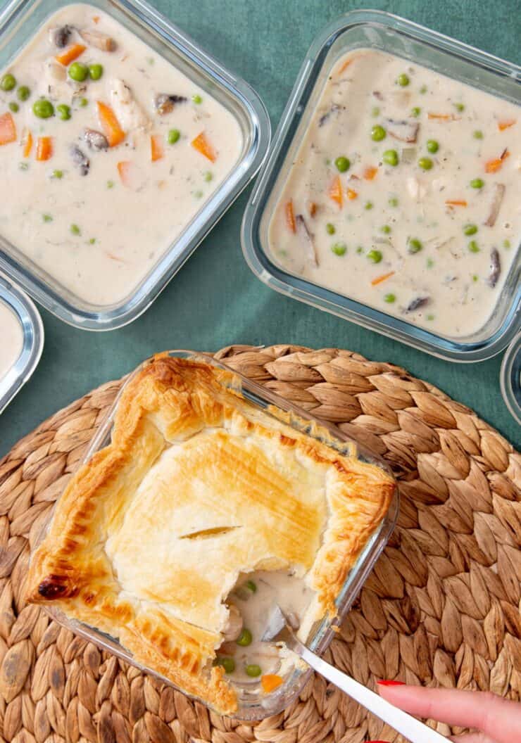 1 cooked chicken pie with pastry cover on straw heat mat with a fork digging in and 4 glass meal prep containers with the pie filling and no pastry.