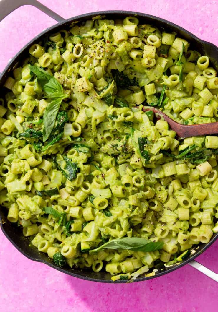 Green Goddess Pasta (using pasta that is shaped like small tubes) and greens in a large pan with a handle and a wooden spoon ready to serve.