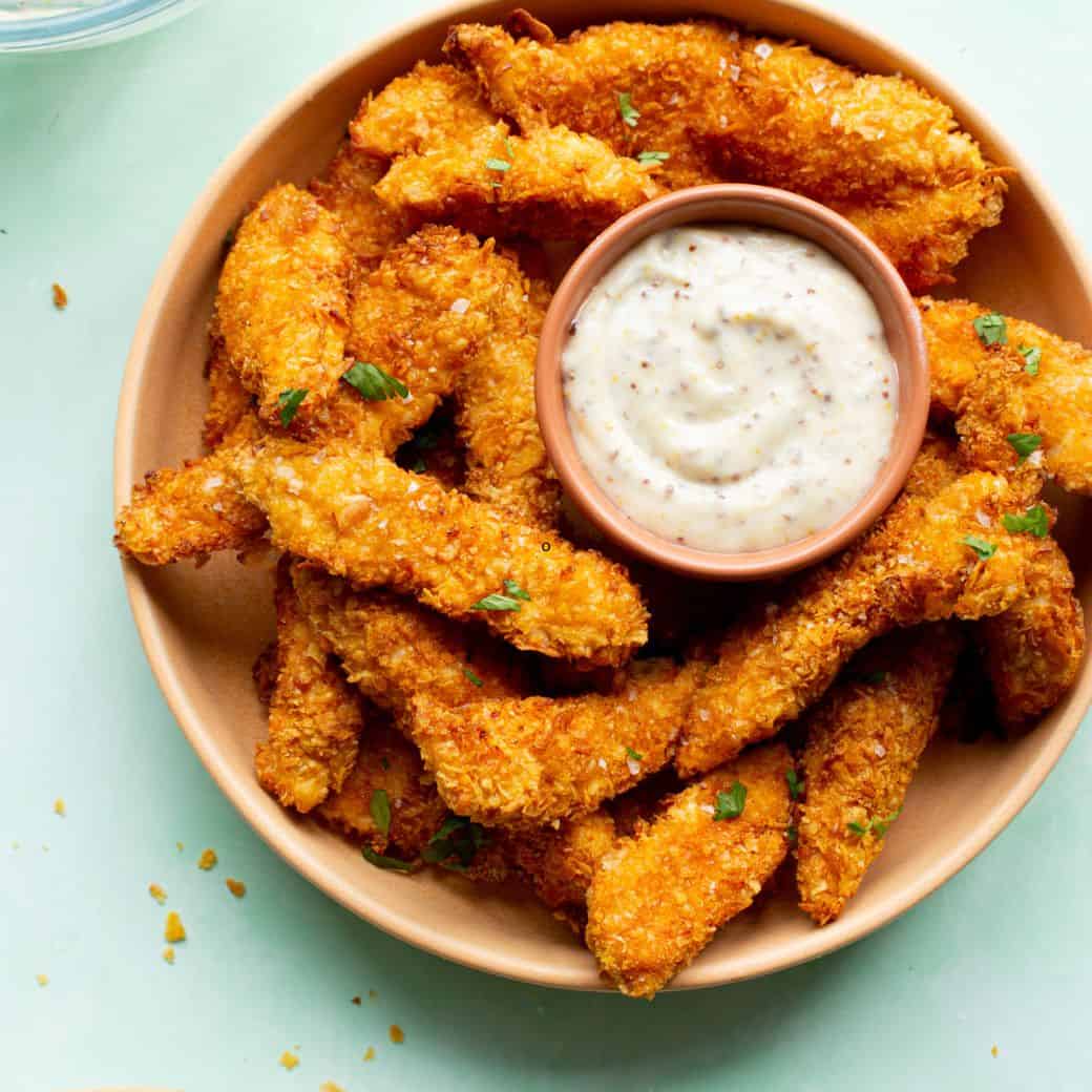 Homemade Chicken Goujons in a bowl with dipping sauce.