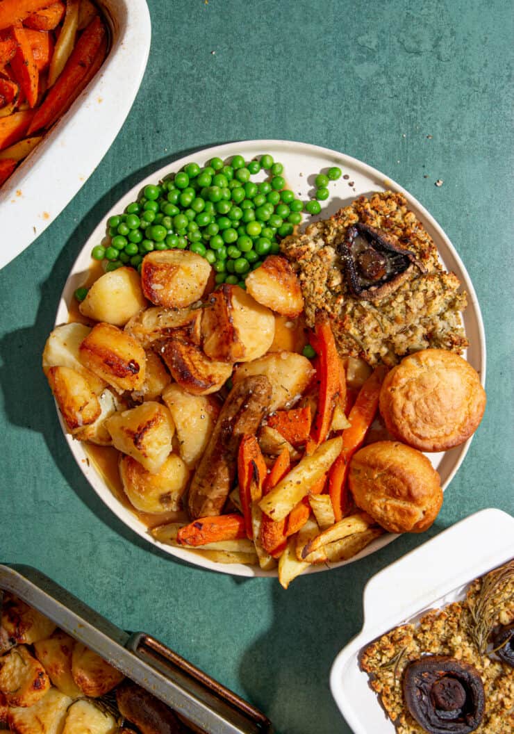 Vegan Roast Dinner with all the trimmings; peas, stuffing, Yorkshire pud, carrots/parsnips sausages.