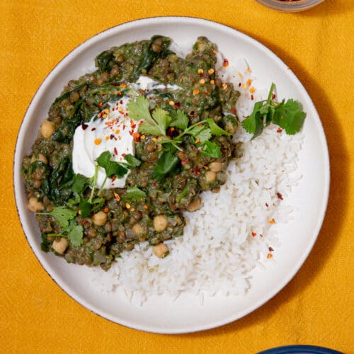 Lentil curry on a plate with white rice and topped with yogurt and coriander.