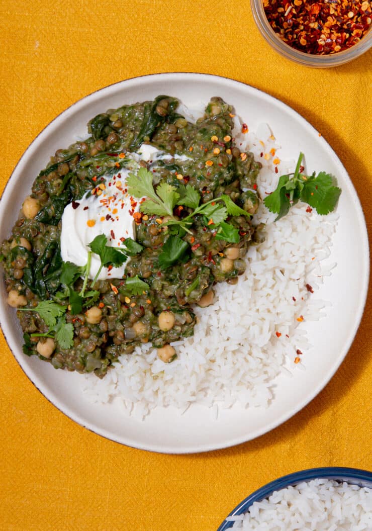 Lentil curry on a plate with white rice and topped with yogurt and coriander.
