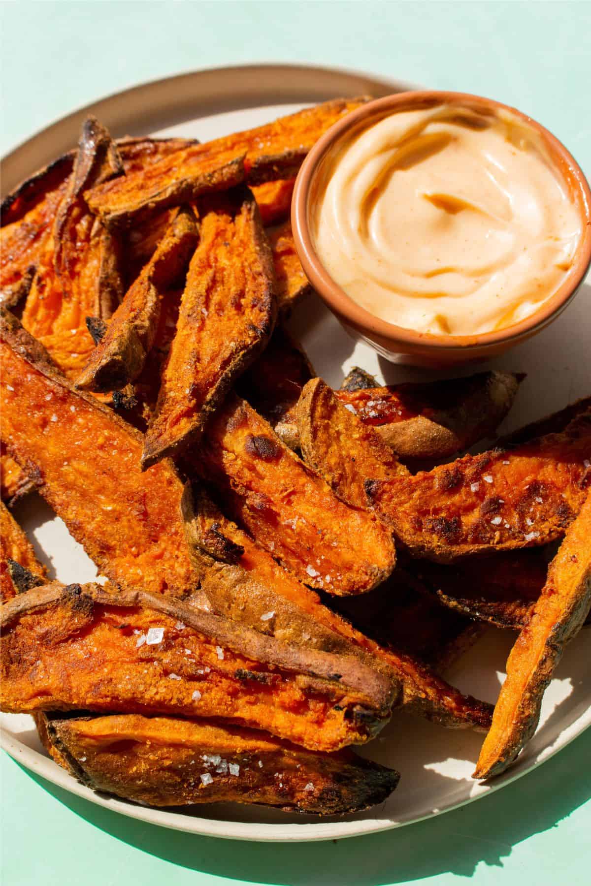 Close up of plate of sweet potato fries with a dipping sauce.