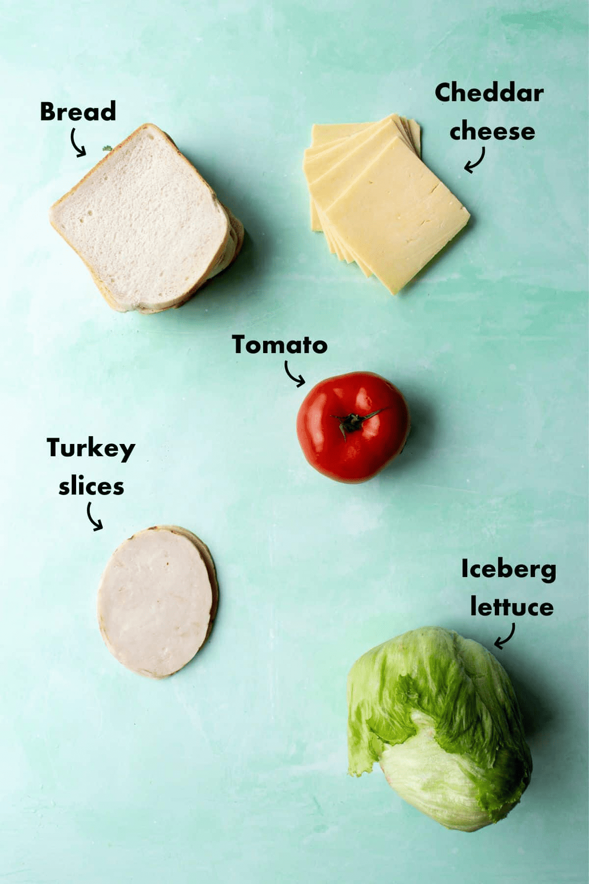 Ingredients to make turkey sandwich, sliced white bread, turkey slices, lettuce, tomato and cheddar cheese slices.