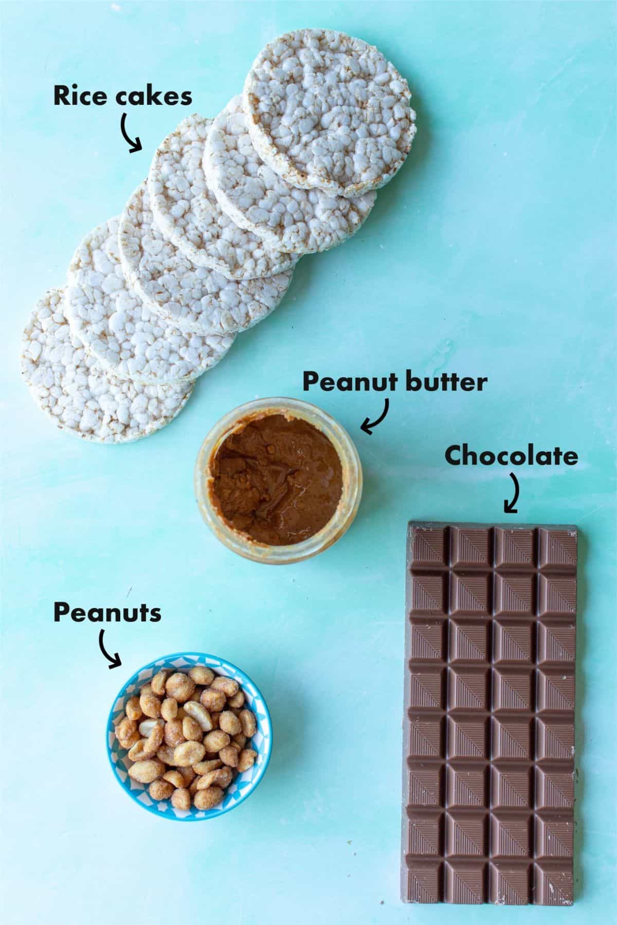Ingredients to make the rice cakes with chocolate and peanut butter, and peanuts laid out on a pale blue back ground and labelled.