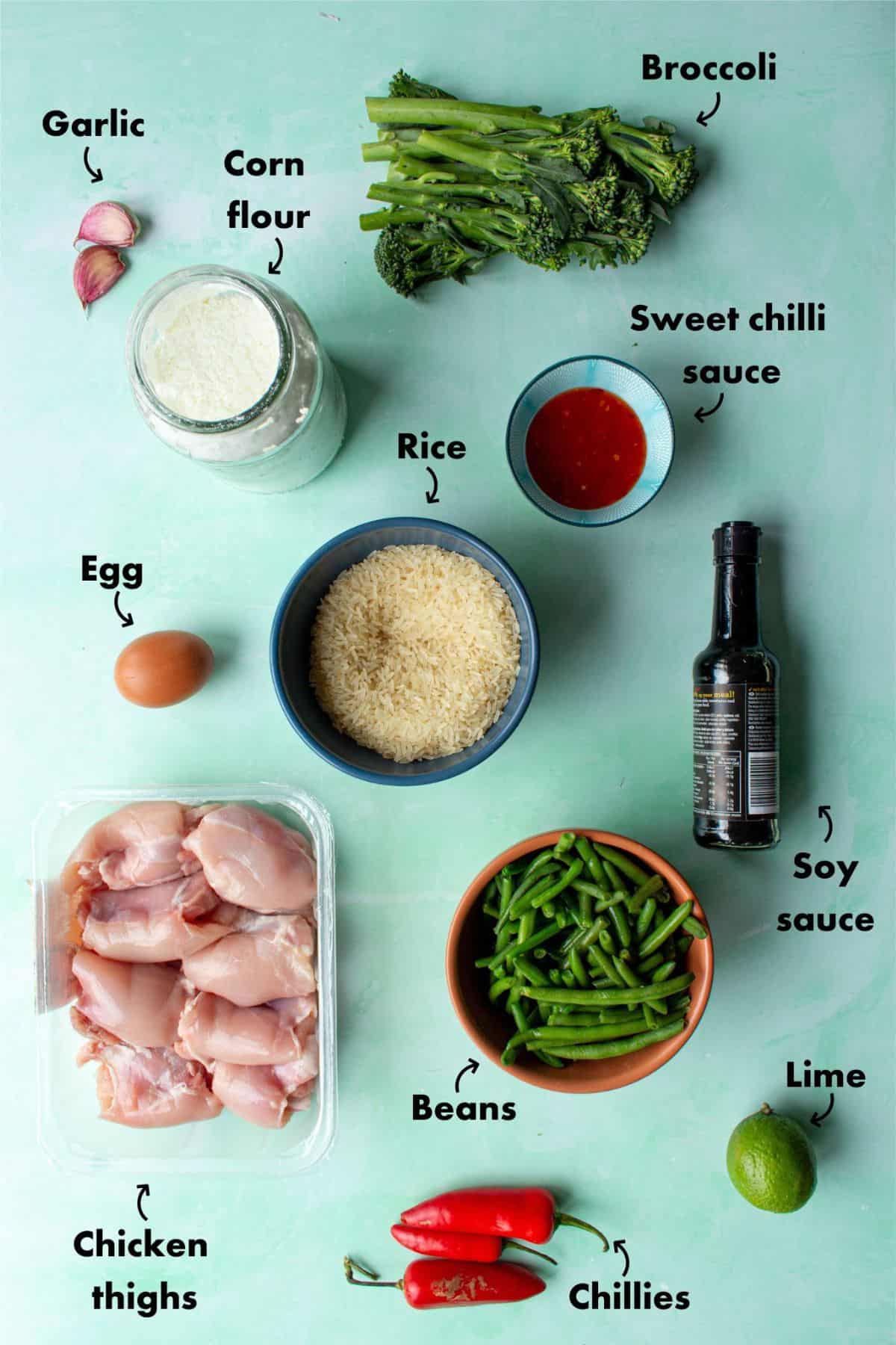 Ingredients to make chilli Chicken laid out on a pale blue background and labelled.