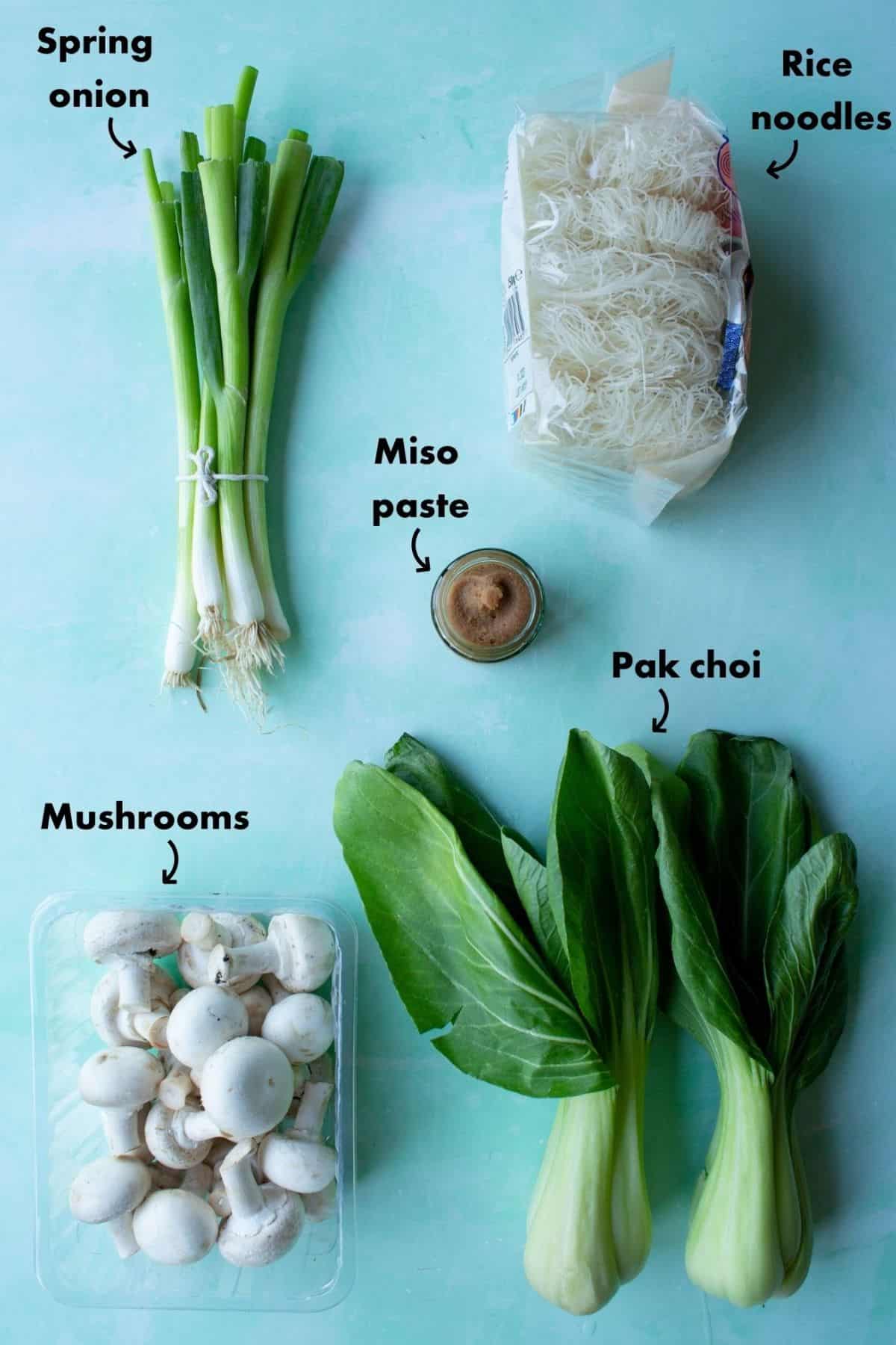 Ingredients to make Instant noodles laid on a pale blue background and labelled.