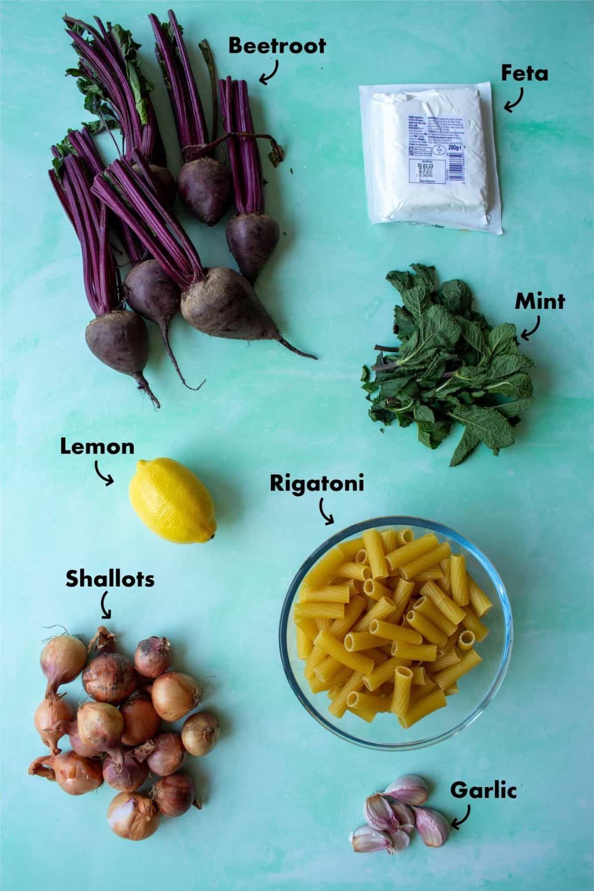 Ingredients to make pasta with beetroot laid out on a pale blue background and labelled.