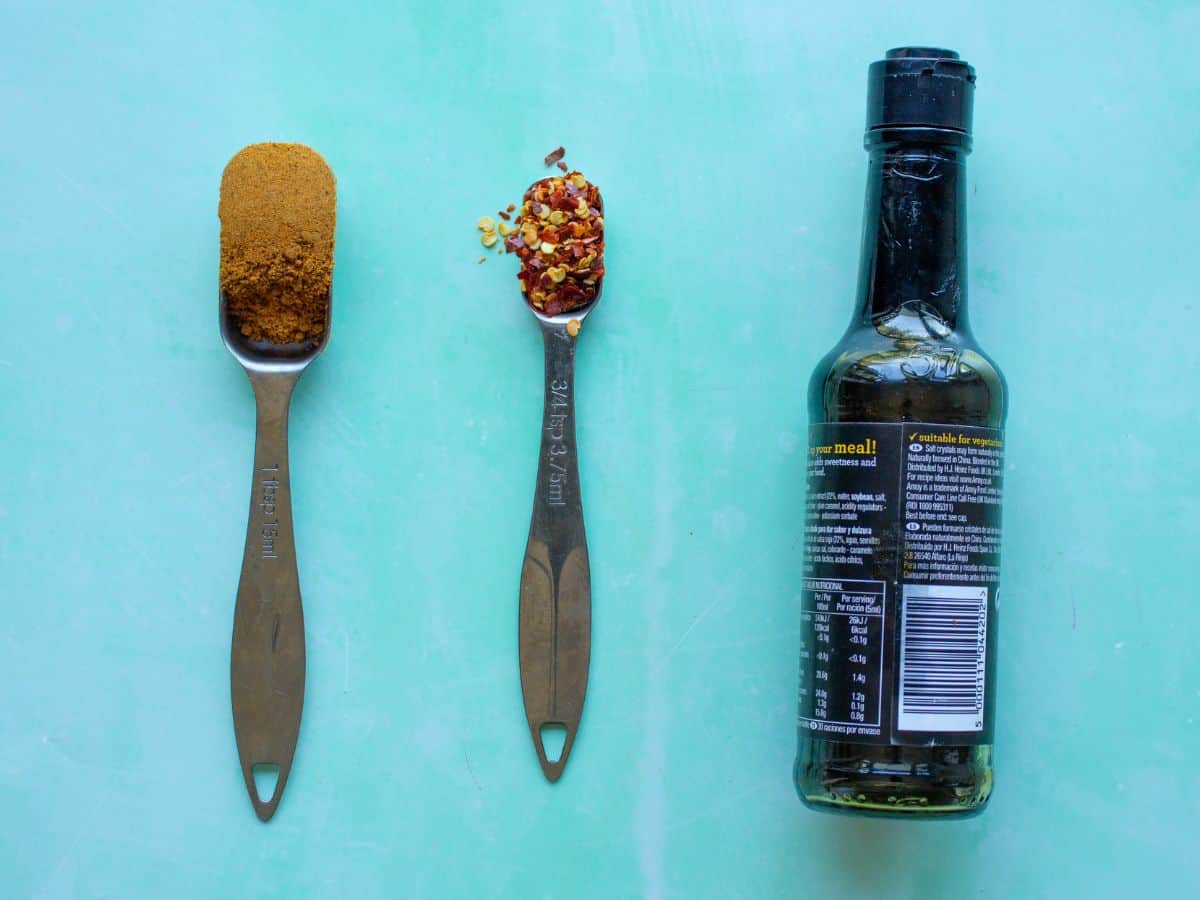 Cupboard essentials for rice recipe laid out on blue background including curry powder, chilli flakes and soy sauce.