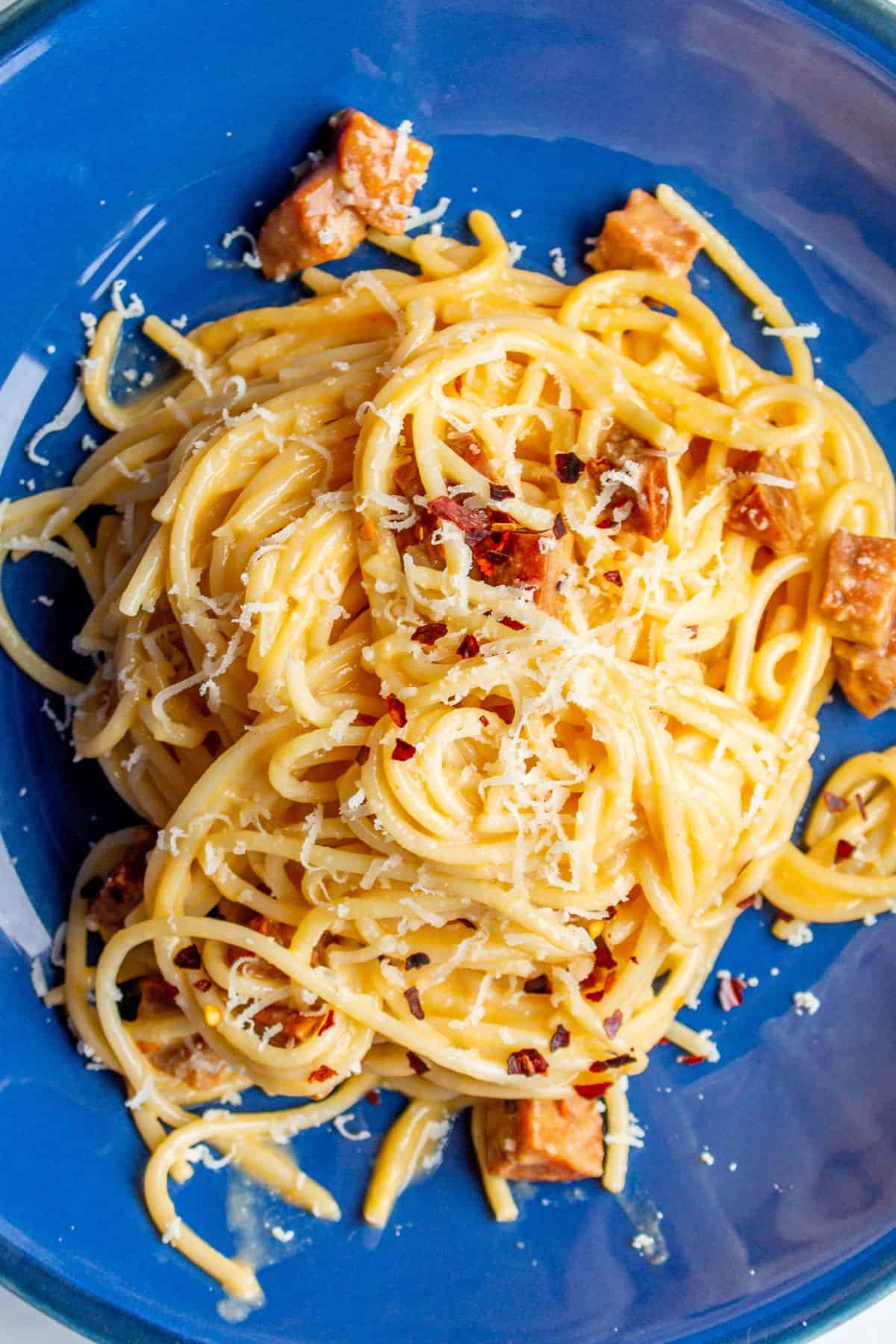Chorizo carbonara served in a blue bowl with grated parmesan.