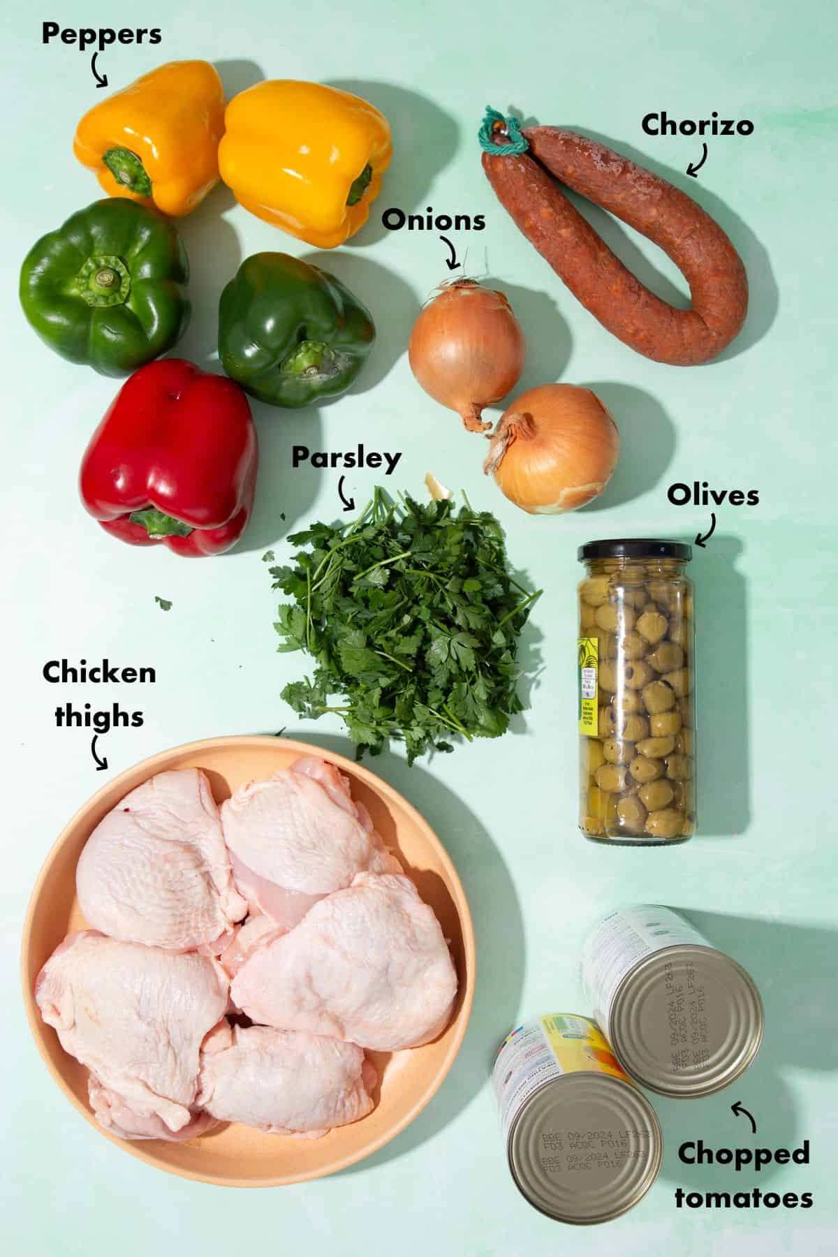 Chicken and chorizo recipe ngredients laid out on a pale blue bakground and labelled