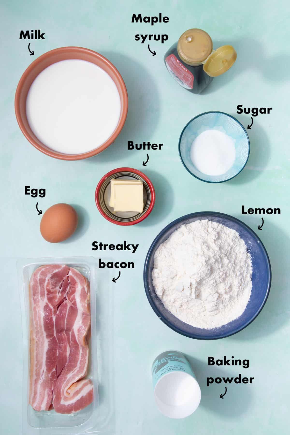 Ingredients to make American pancakes laid out on a pale blue background and labelled.
