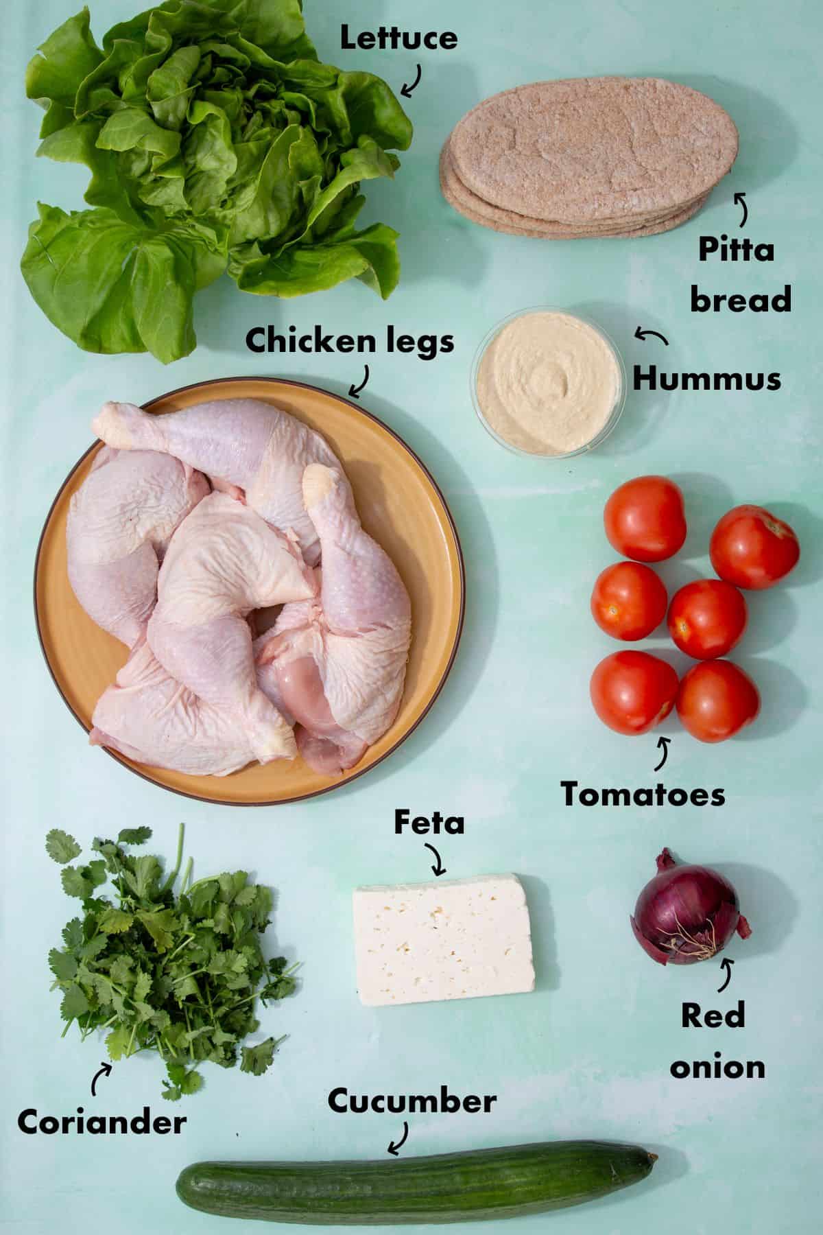 Ingredients to make Chciken Shawarma with salad laid out on a pale blue background and labelled.