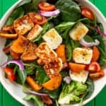 Salad in a bowl with golden browned halloumi, butternut squash, red onion and tomatoes.