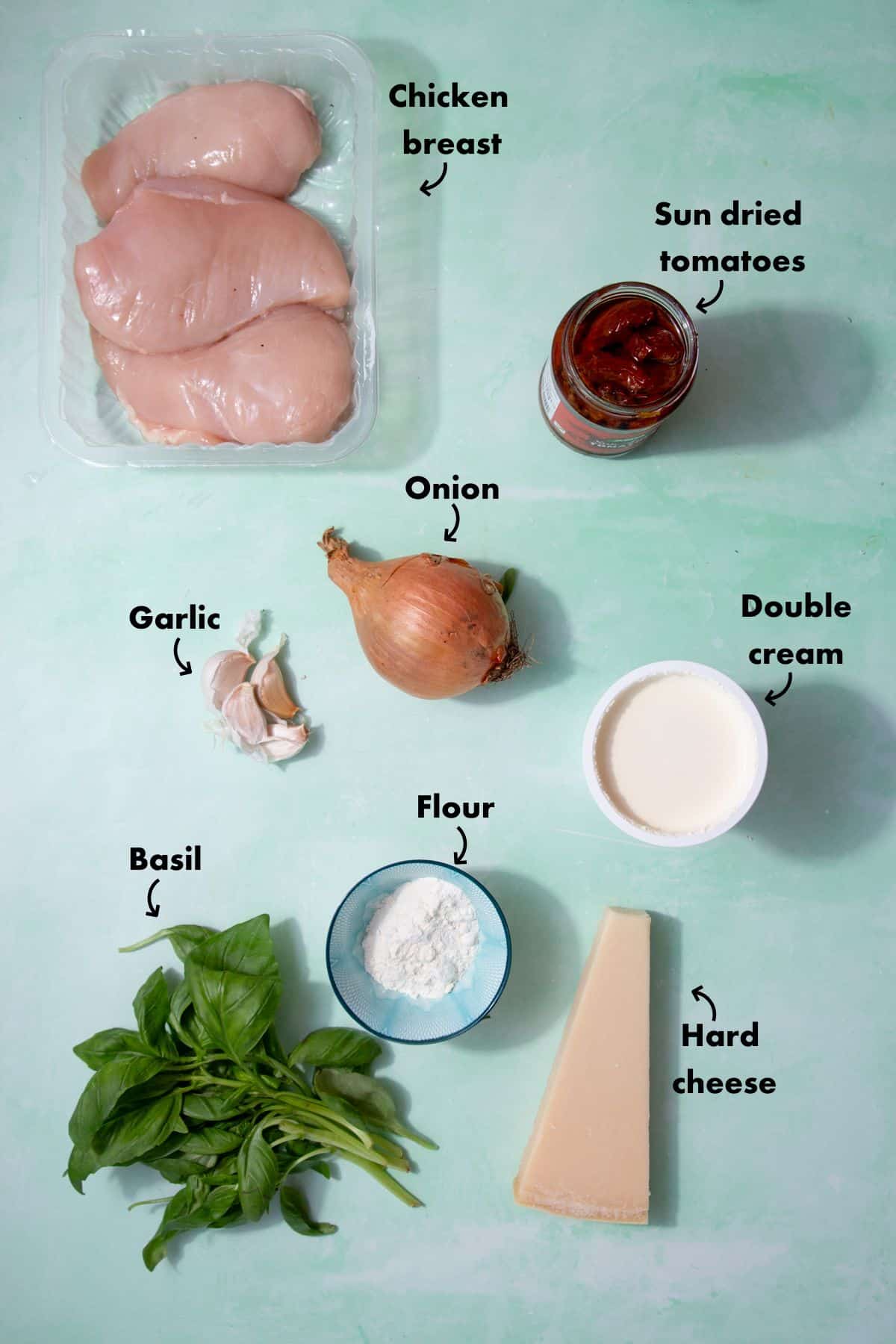 Ingredients to make creamy tomato chicken recipes laid out on a pale blue back ground and labelled.