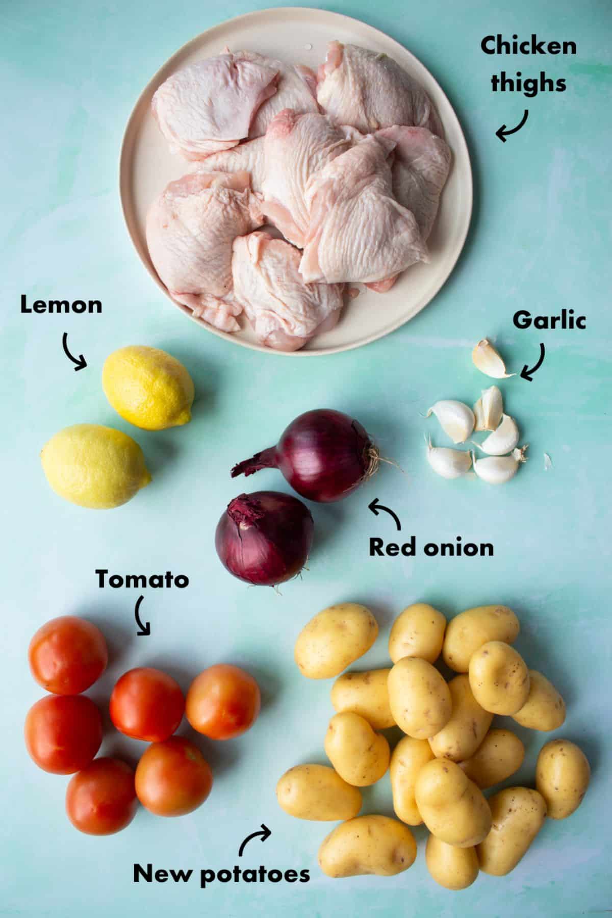 Ingredients to make the chicken thigh tray bake laid out on a pale blue background and labelled.