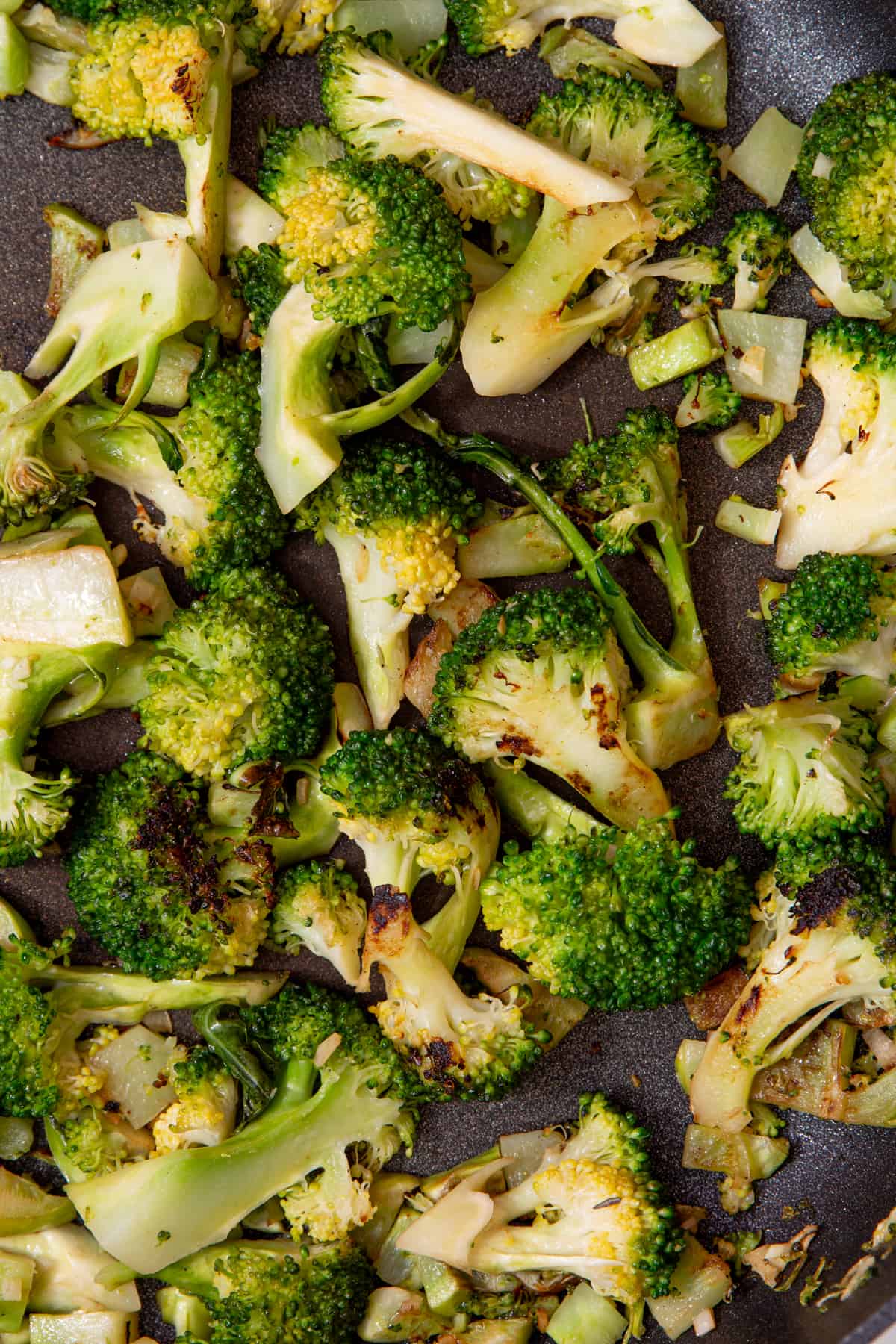 Close up of charred broccoli florets and browned stalks in a pan.