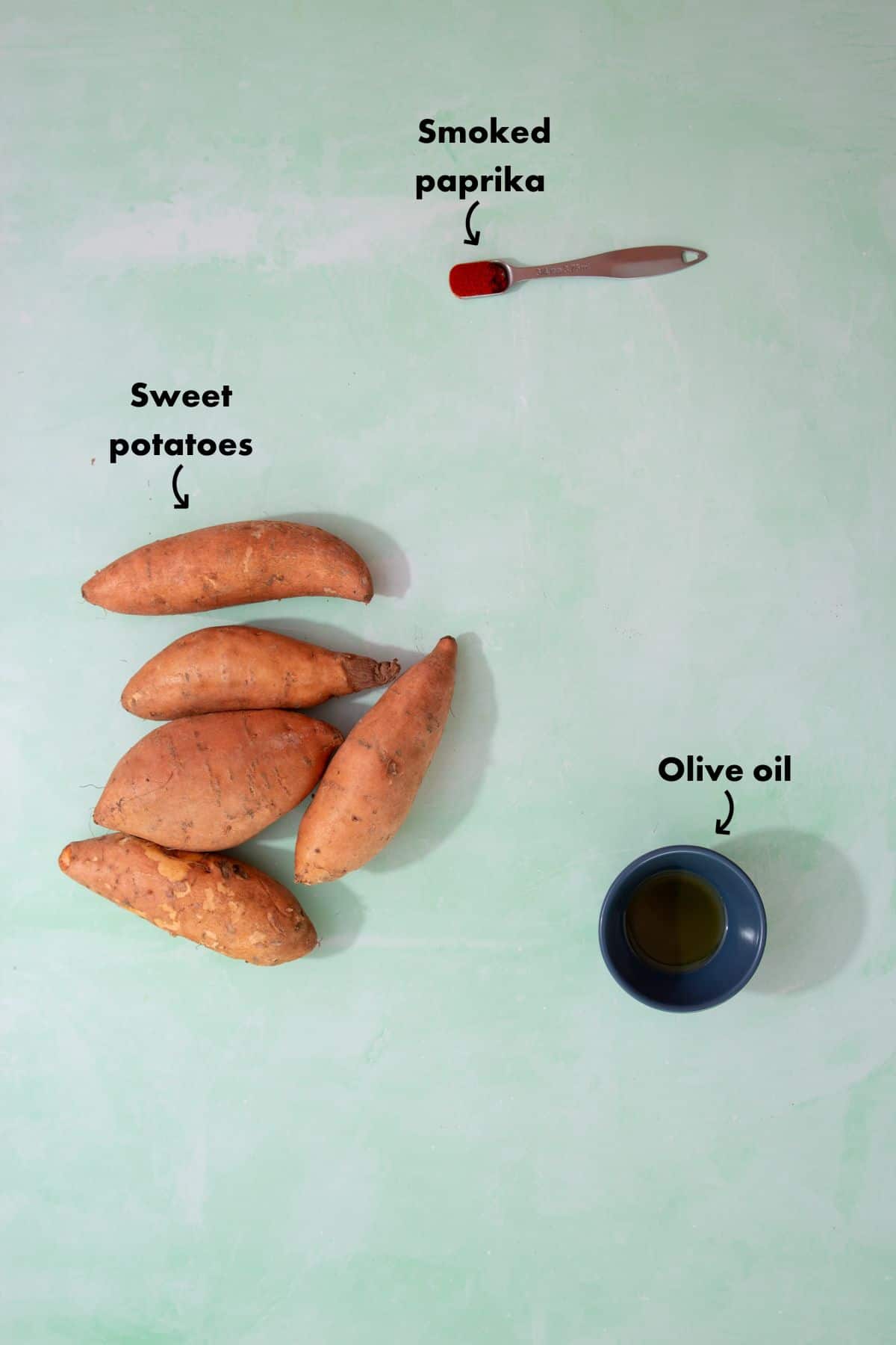 Ingredients to make the sweet ptoato recipe laid out on a plae blue background and labelled.
