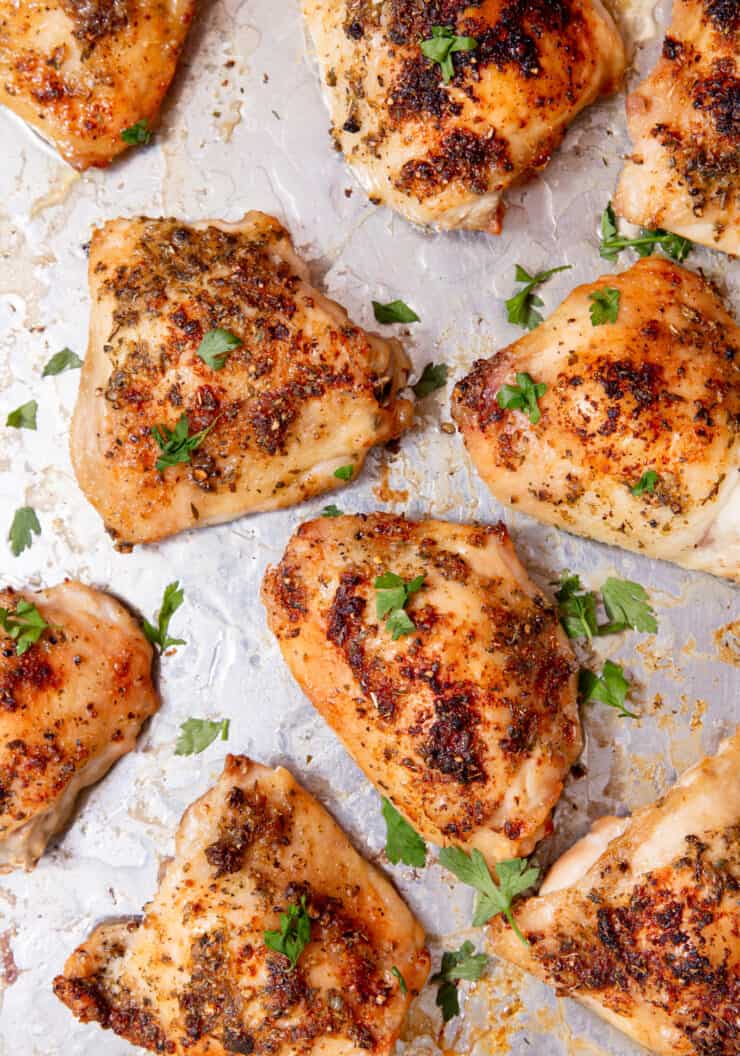 Chicken thighs on a silver baking tray topped with parsley