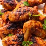 Peri peri chicken thighs, charred and golden browned served on a plate.