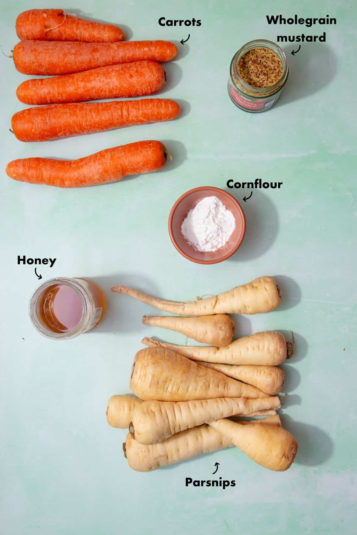 Ingredients to make a carrots and parsnips recipe recipe laid out on aple blue back ground and labelled.