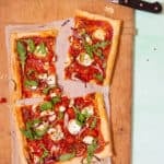 A Goat's cheese tart laid out on parchment paper on a chopping board.