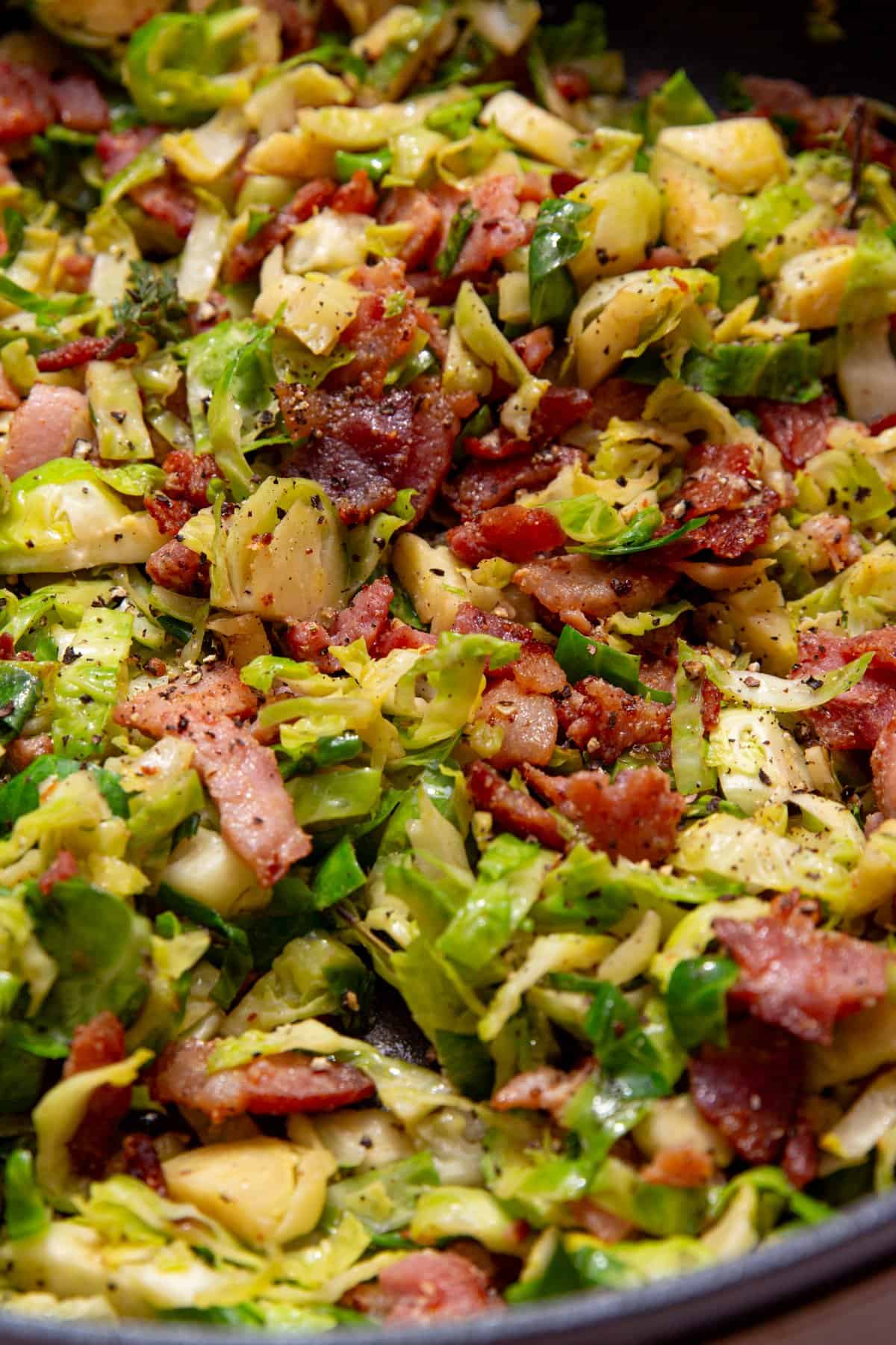 Sliced and cooked Brussel sprouts with browned bacon pieces with pepper added..