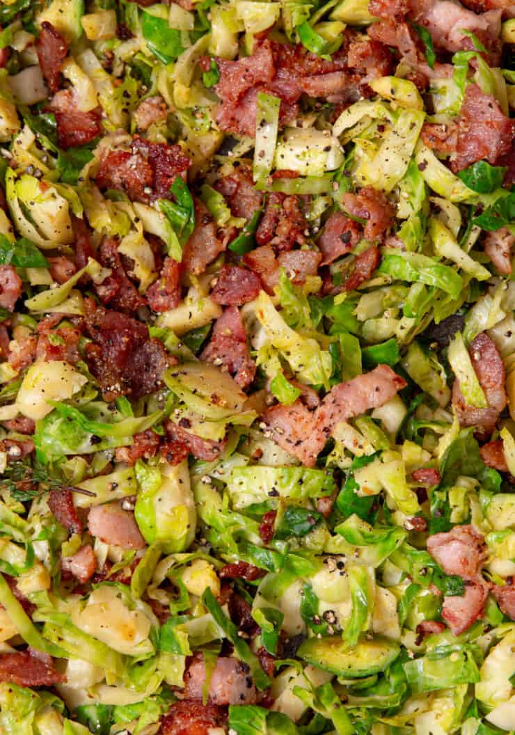 Close up of sliced and fried Brussel sprouts and browned bacon pieces.