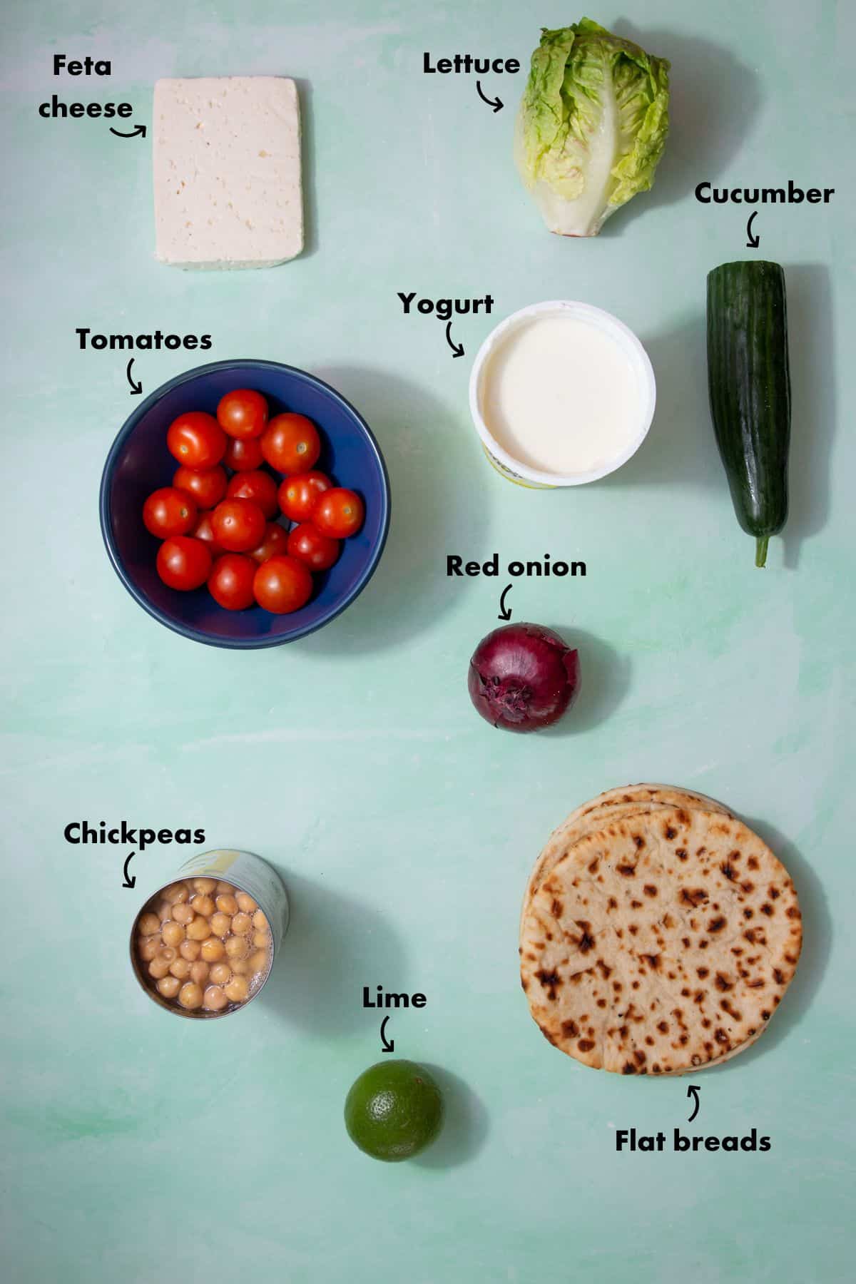 Ingredients to make a chickpea and feta wrap liad out on a pale blue background and labelled.