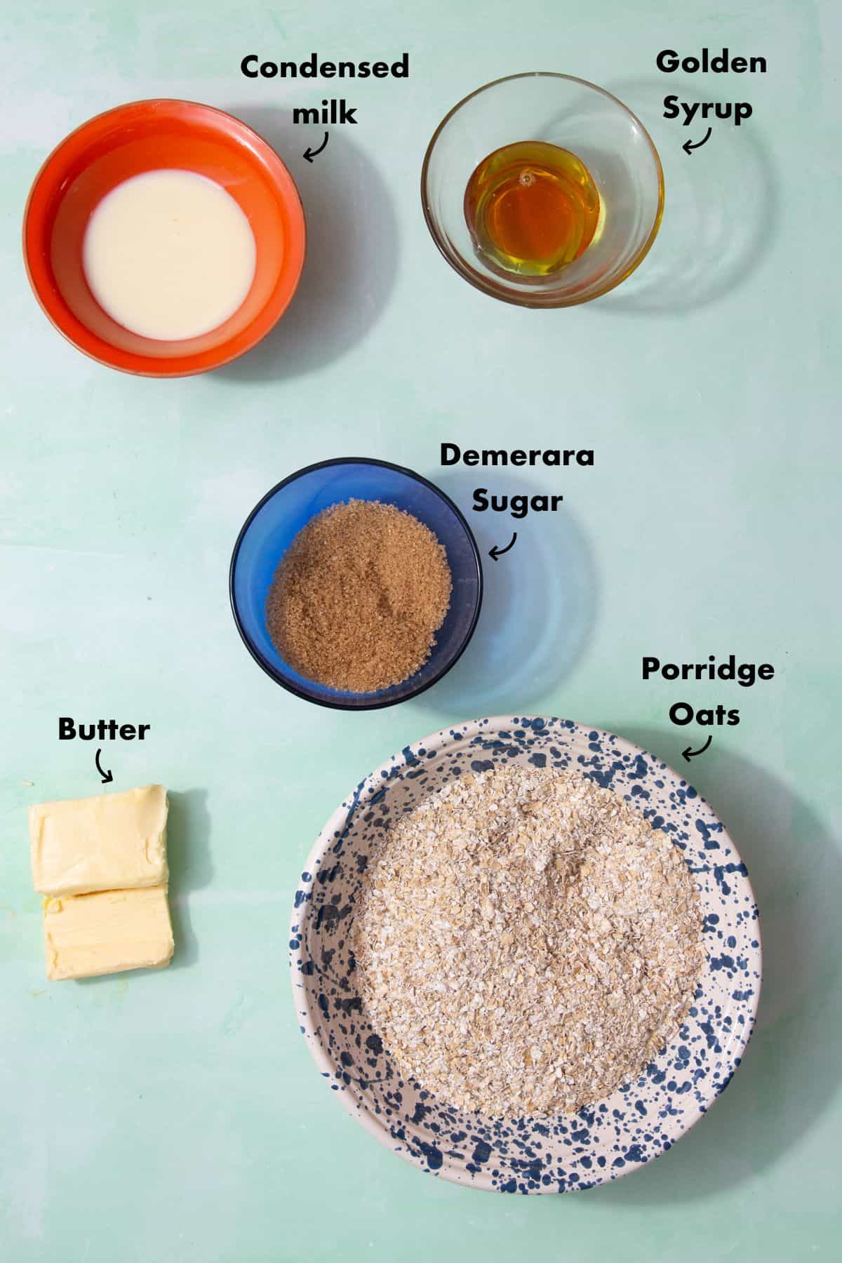 Ingredients to make flapjacks laid out on a pale blue background and labelled.