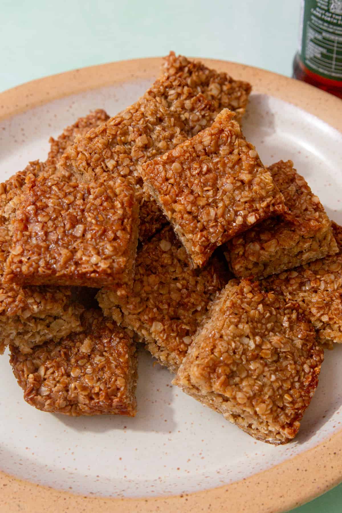 Flapjack squares piled on a plate witha pale green background.