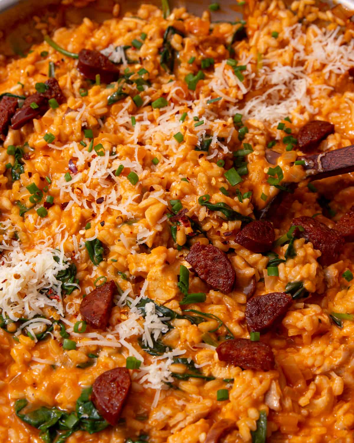 Risotto with pieces of chorizo, chicken, stirred with a wooden spoon and topped with chopped chives and parmesan.
