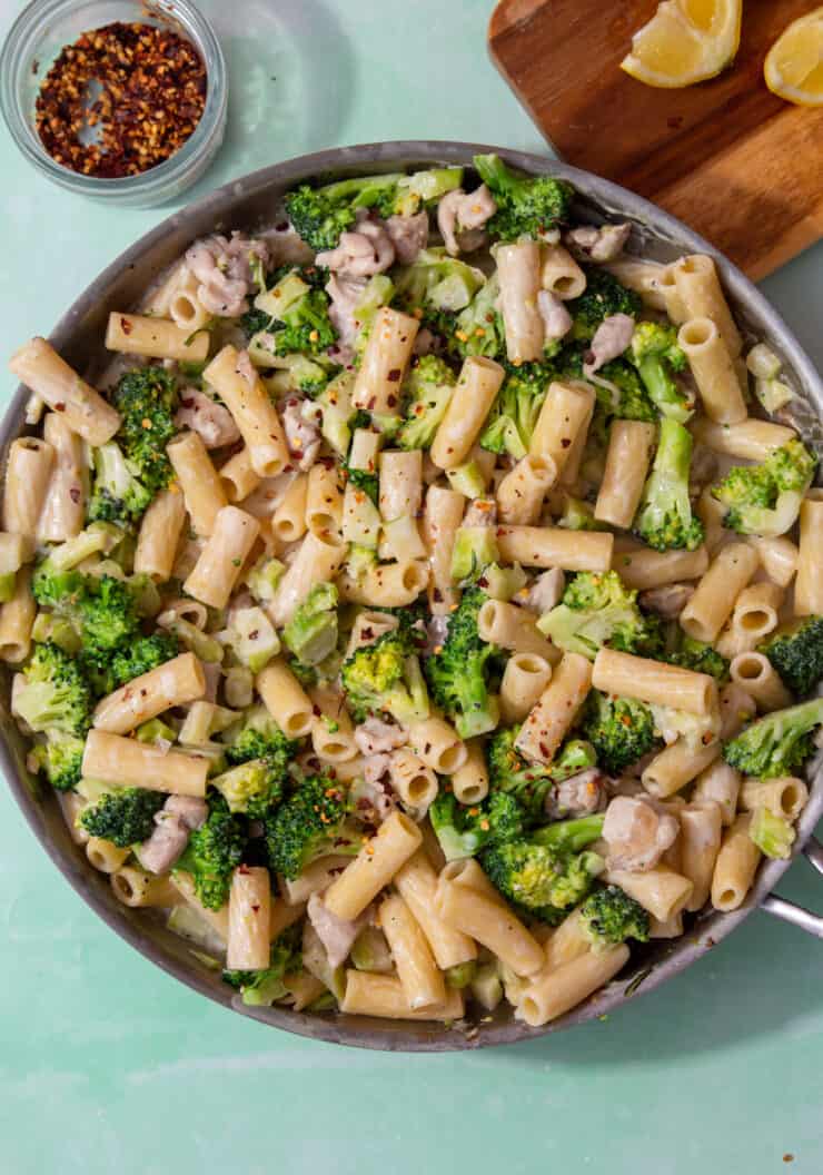 A large pan with rigatoni pasta, broccoli and chicken. in a creamy sauce.