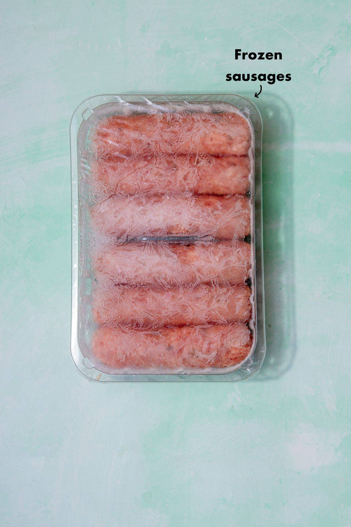 6 frozen saiusages in a plastic container on a pale blue background and labelled.